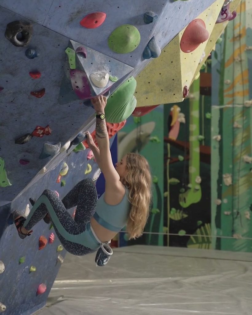 A climber reaching on colourful holds